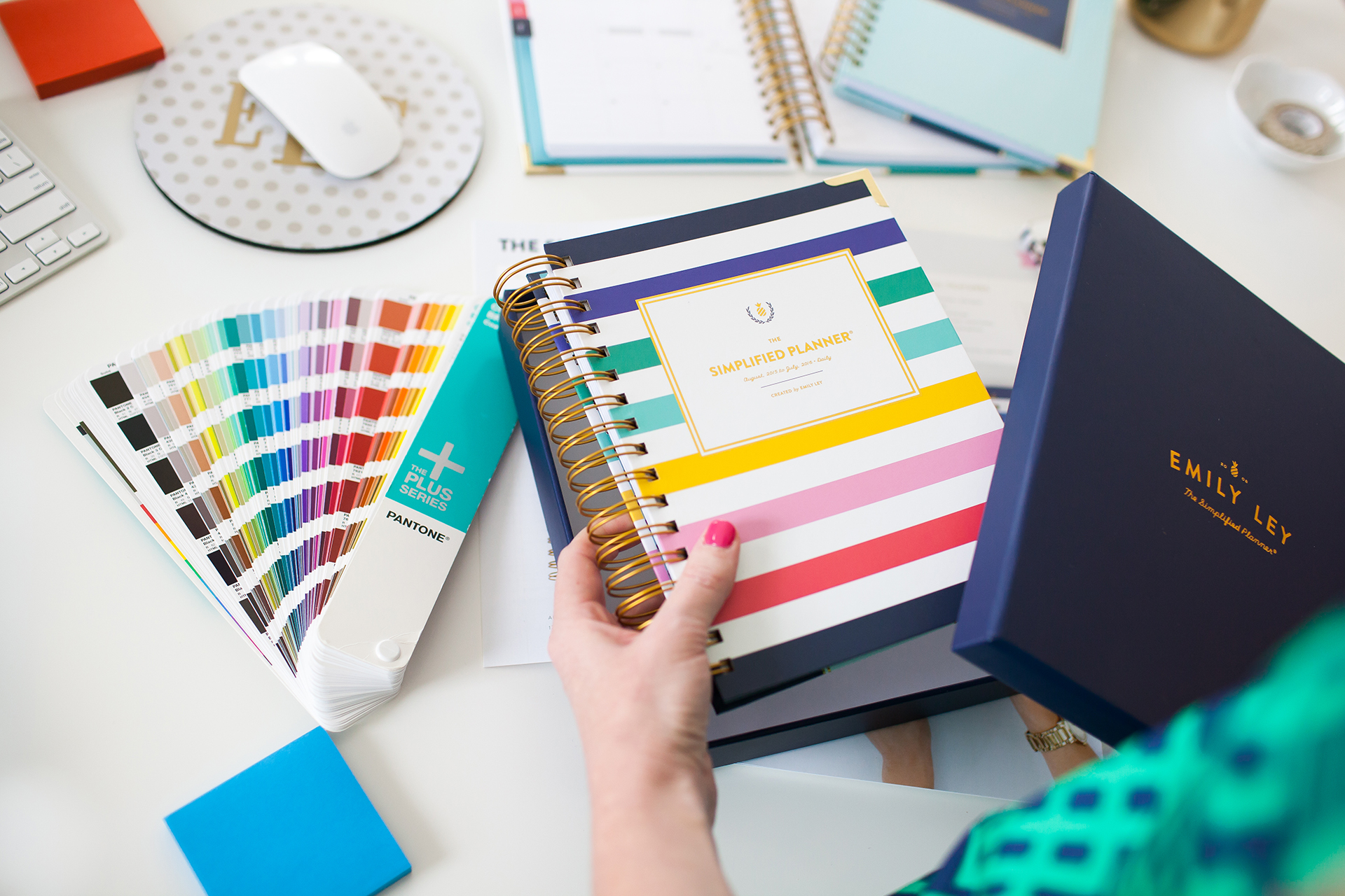 Hands holding a planner surrounded by color swatches and other office items