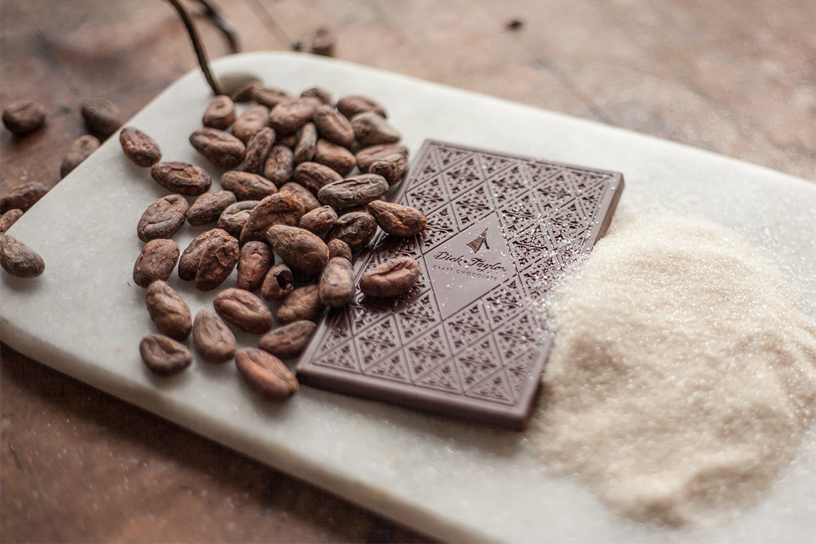 Dick Taylor Chocolate arranged on a marble board with beans and sugar