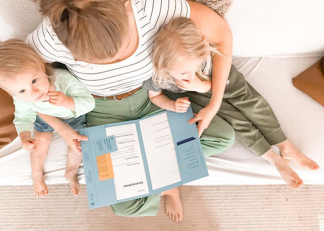 Parent with two small children holding an open Trust and WIll package