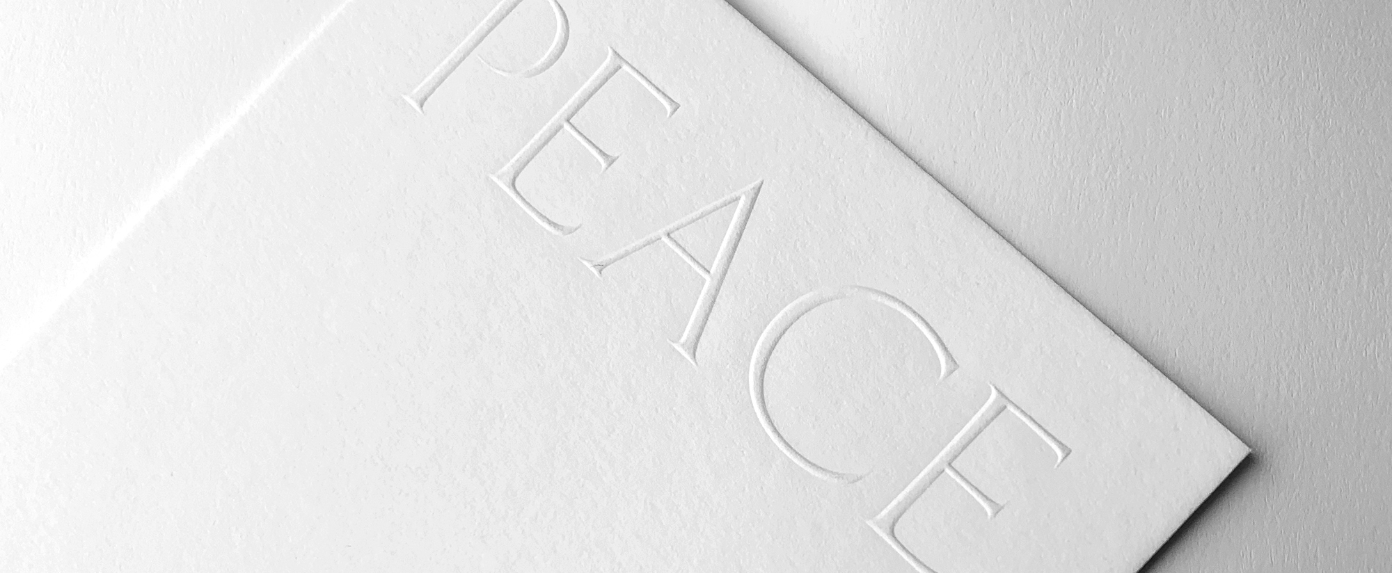 Detail of blind embossed card that reads "peace"
