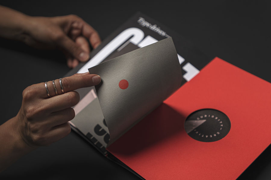 hands holding the brochure open on a black background