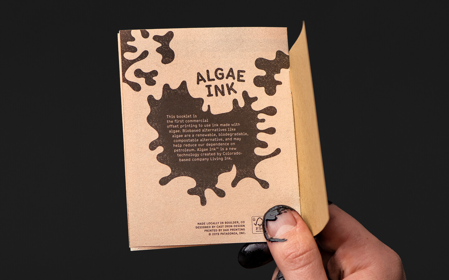 A hand holding a small booklet printed with algae ink