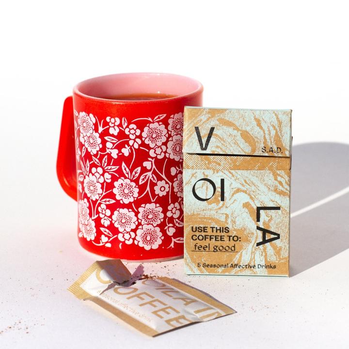 Voila Coffee packaging next to a coffee mug