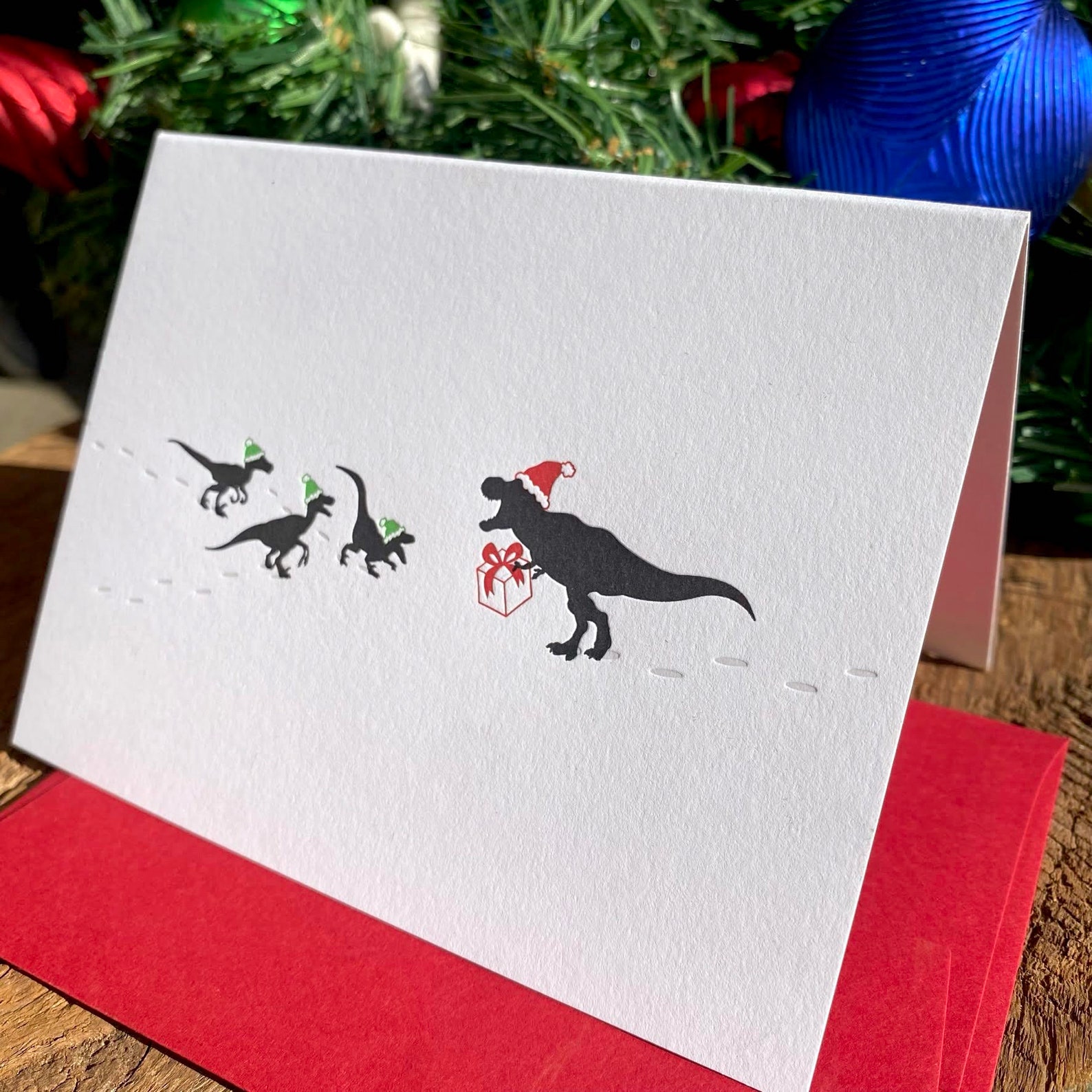 dinosaurs wearing santa hats on a holiday card