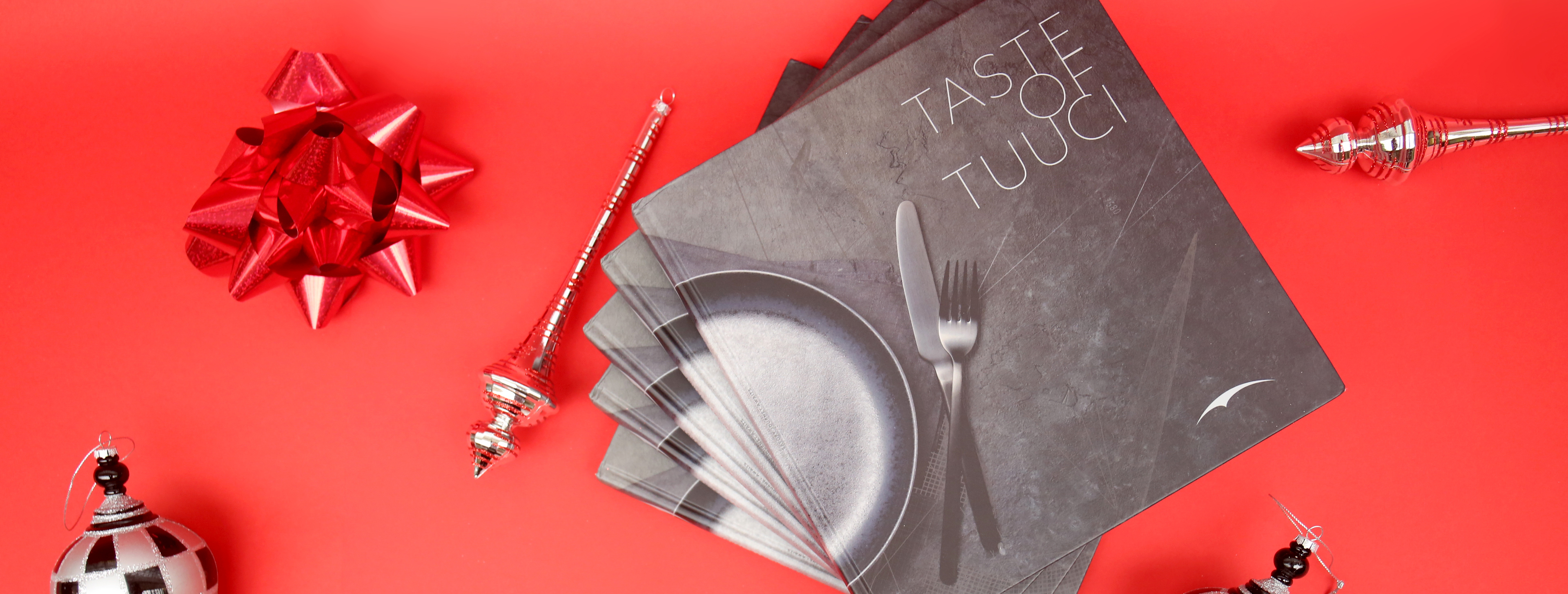 Taste of Tuuci cookbooks on a red background with holiday ornaments