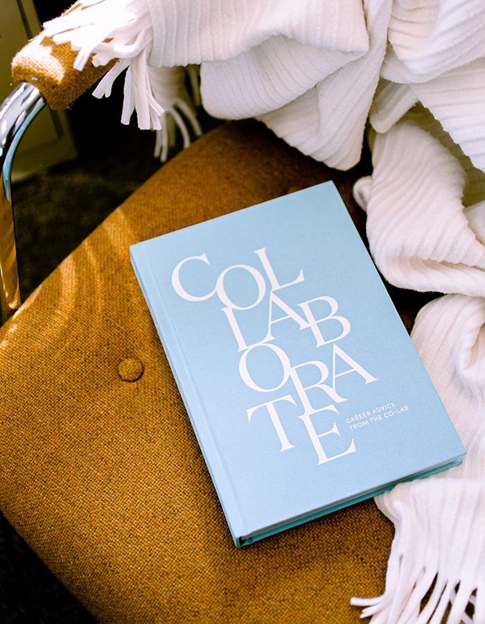 The Collaborate book on a midcentury modern, mustard-colored chair