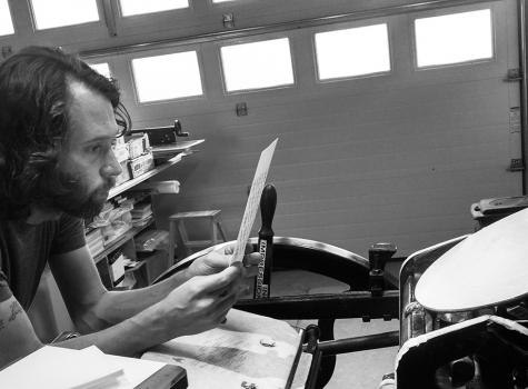 black and white photograph of Chris Fritton working at a letterpress machine