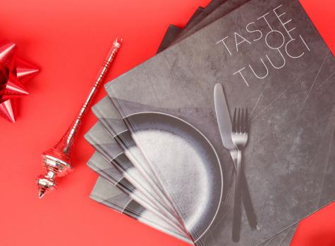 Taste of Tuuci cookbooks on a red background with holiday ornaments
